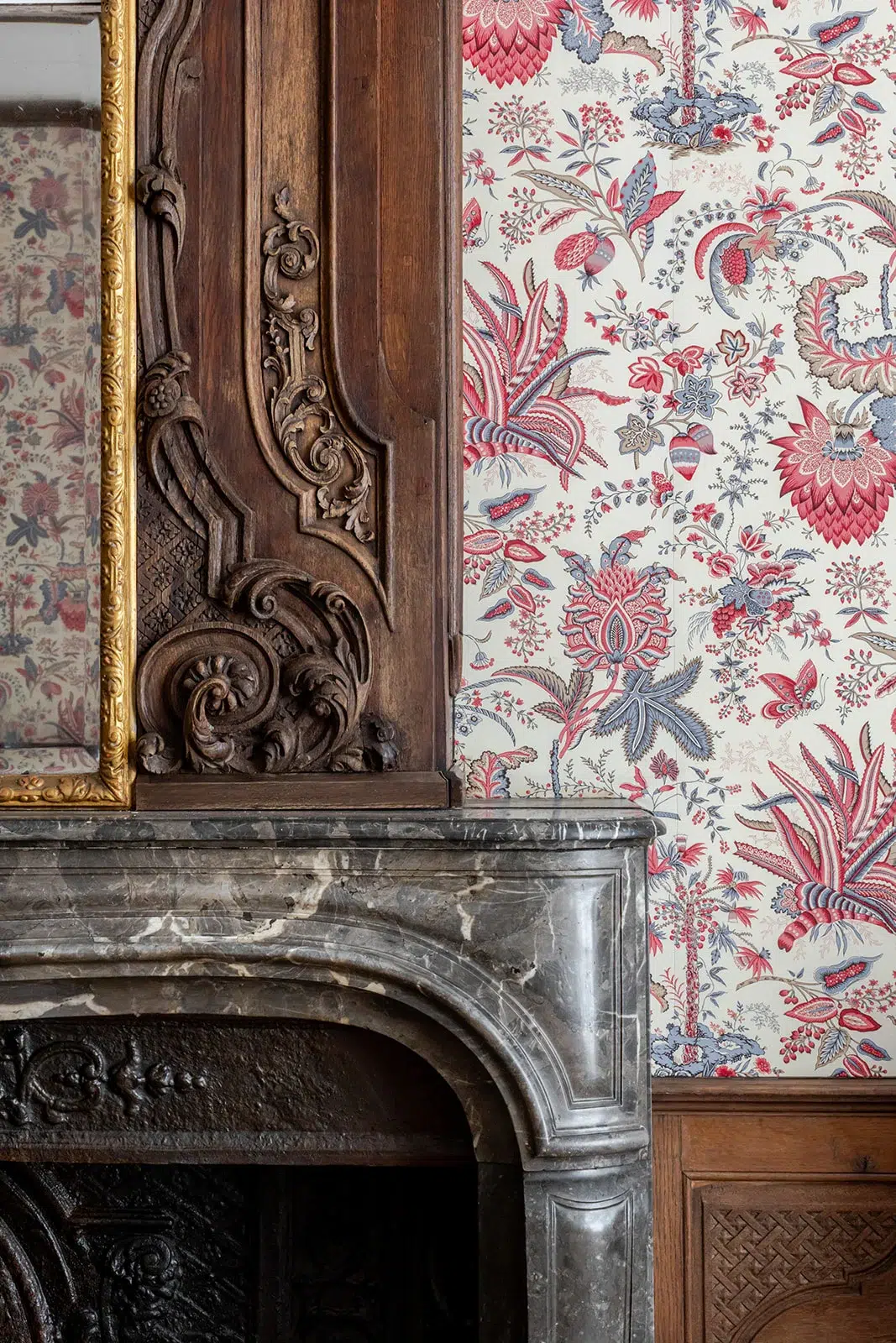 Carved wood and marble fireplace with bespoke floral tapestry at Faubourg 21 hotel in Brussels.